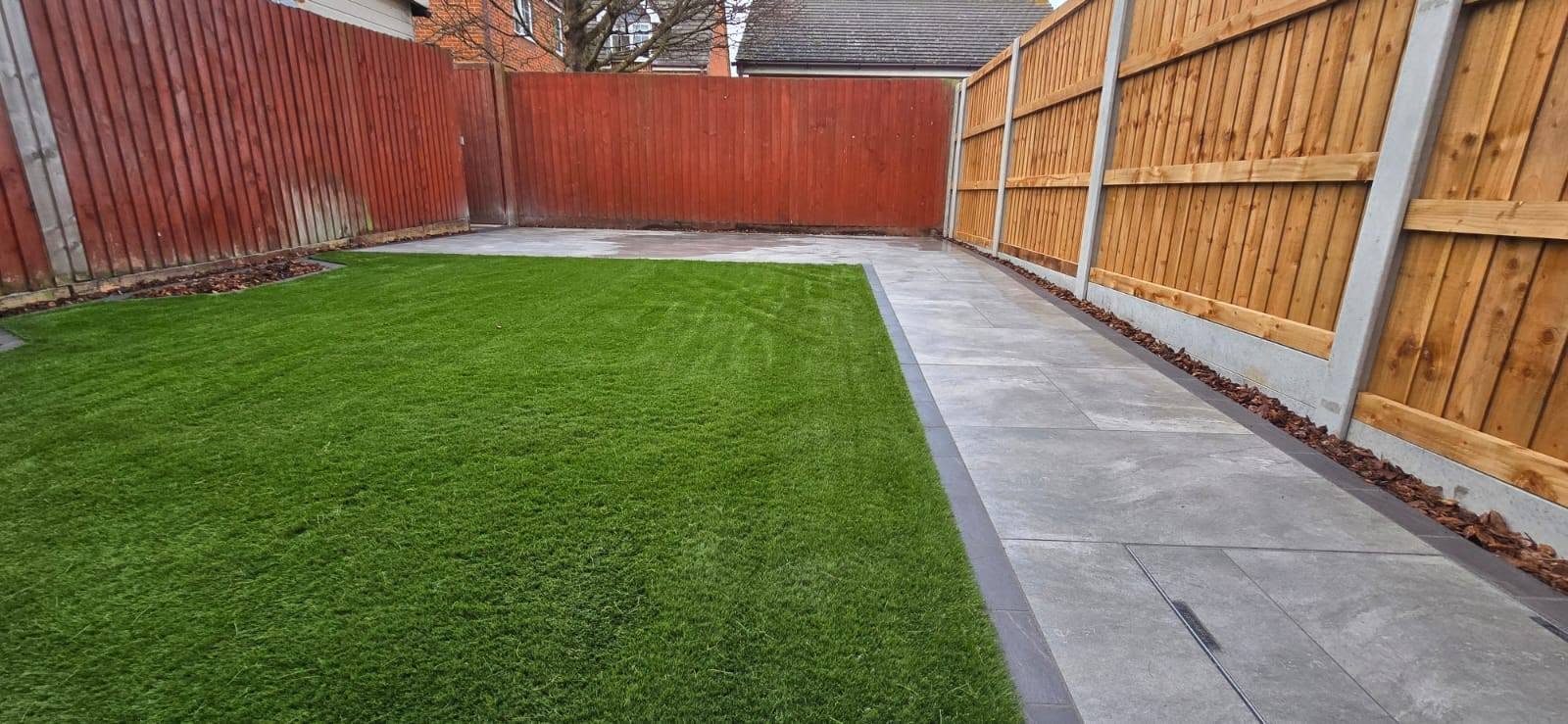 New lawn with a porcelain path along a red fence